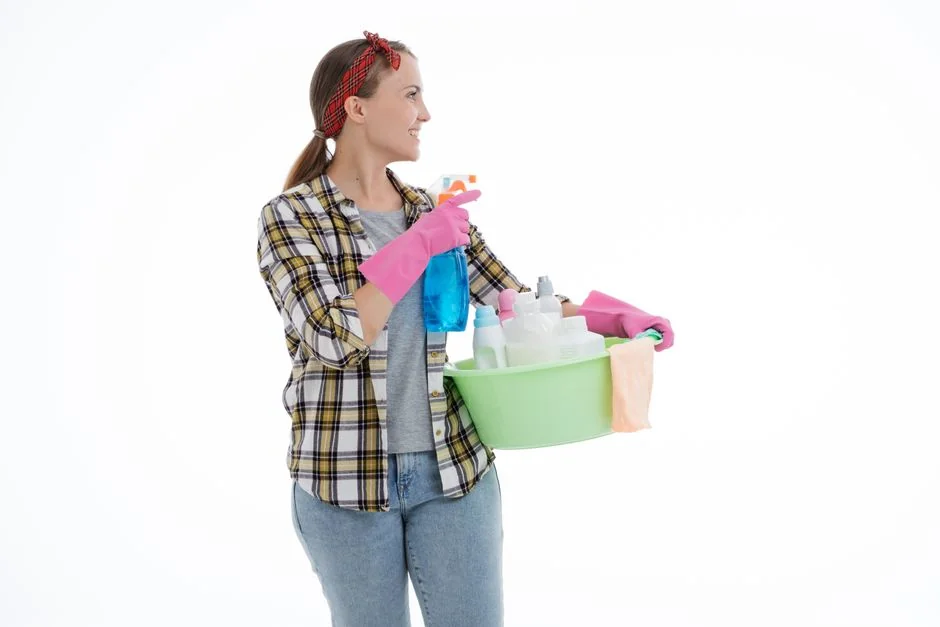 A blue-gloved hand holding a cleaning spray bottle on a yellow background.